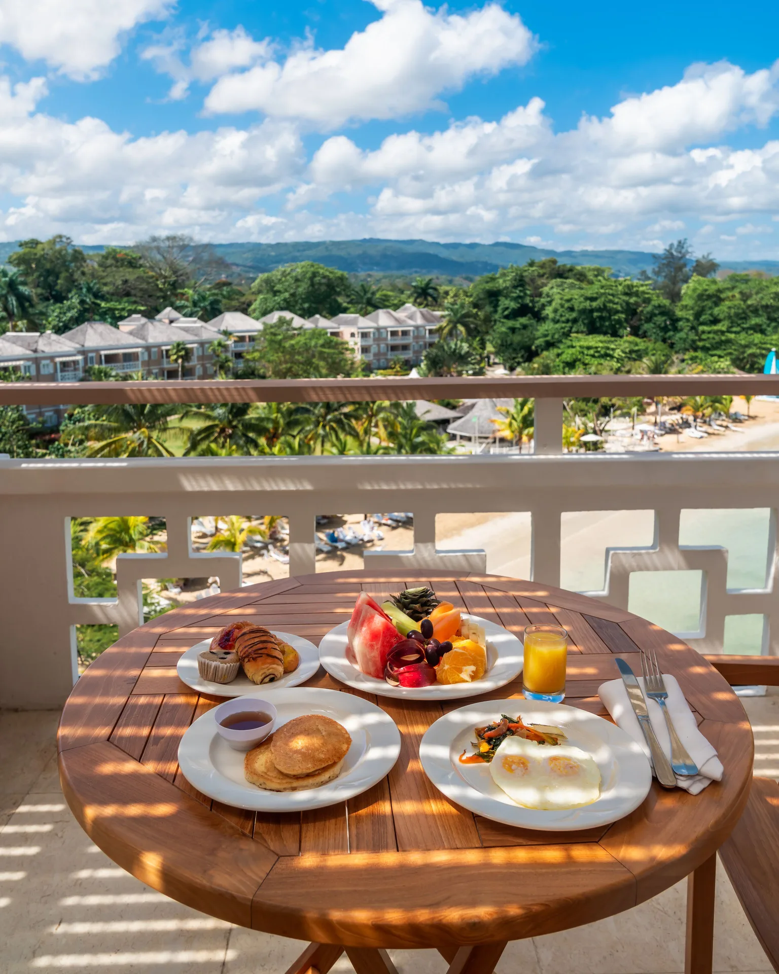 Breakfast plates on a balcony table overlooking Couples Sans Souci and the beach.