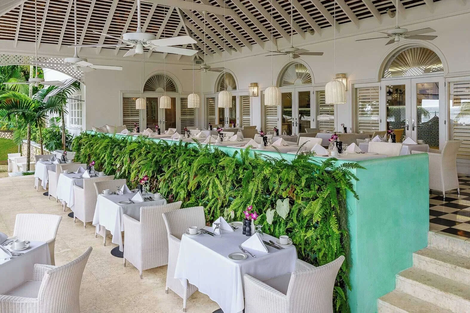 An open-air dining terrace with white table settings at Couples Sans Souci.
