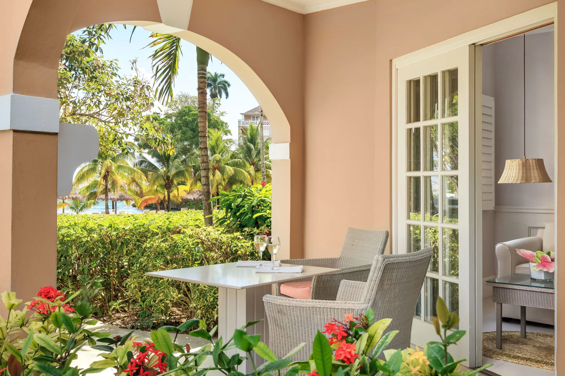 Beach Front Suite patio with table and tropical garden view at Couples Sans Souci.