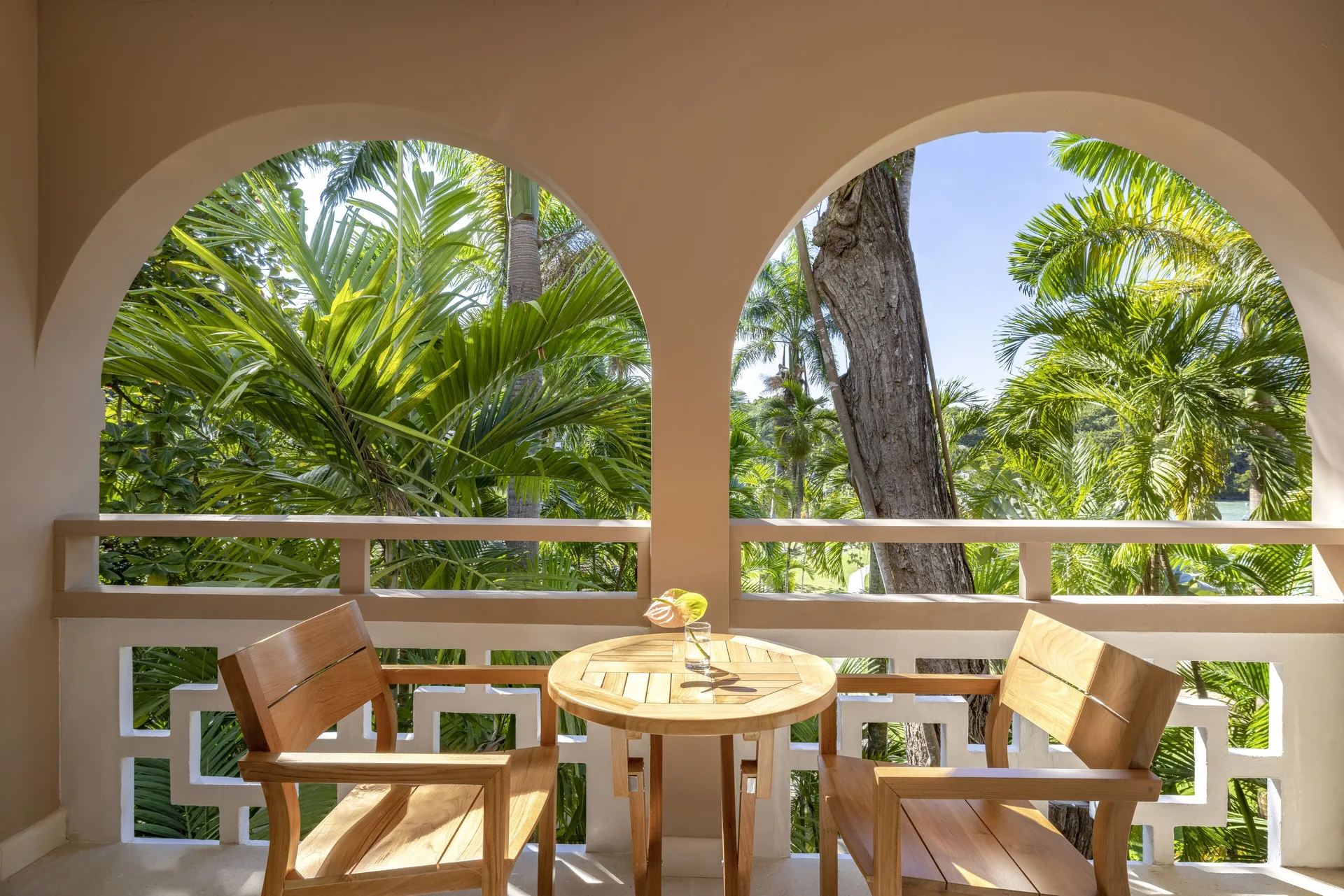 Deluxe Garden Suite balcony with two chairs and tropical palms at Couples Sans Souci.