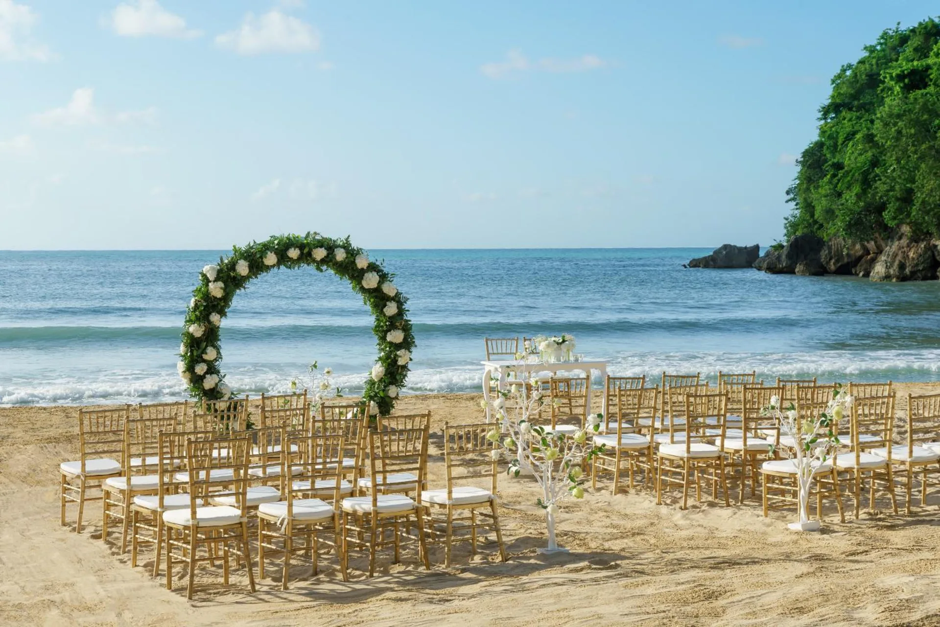 Beach wedding ceremony setup with floral arch by the sea at Couples Sans Souci.