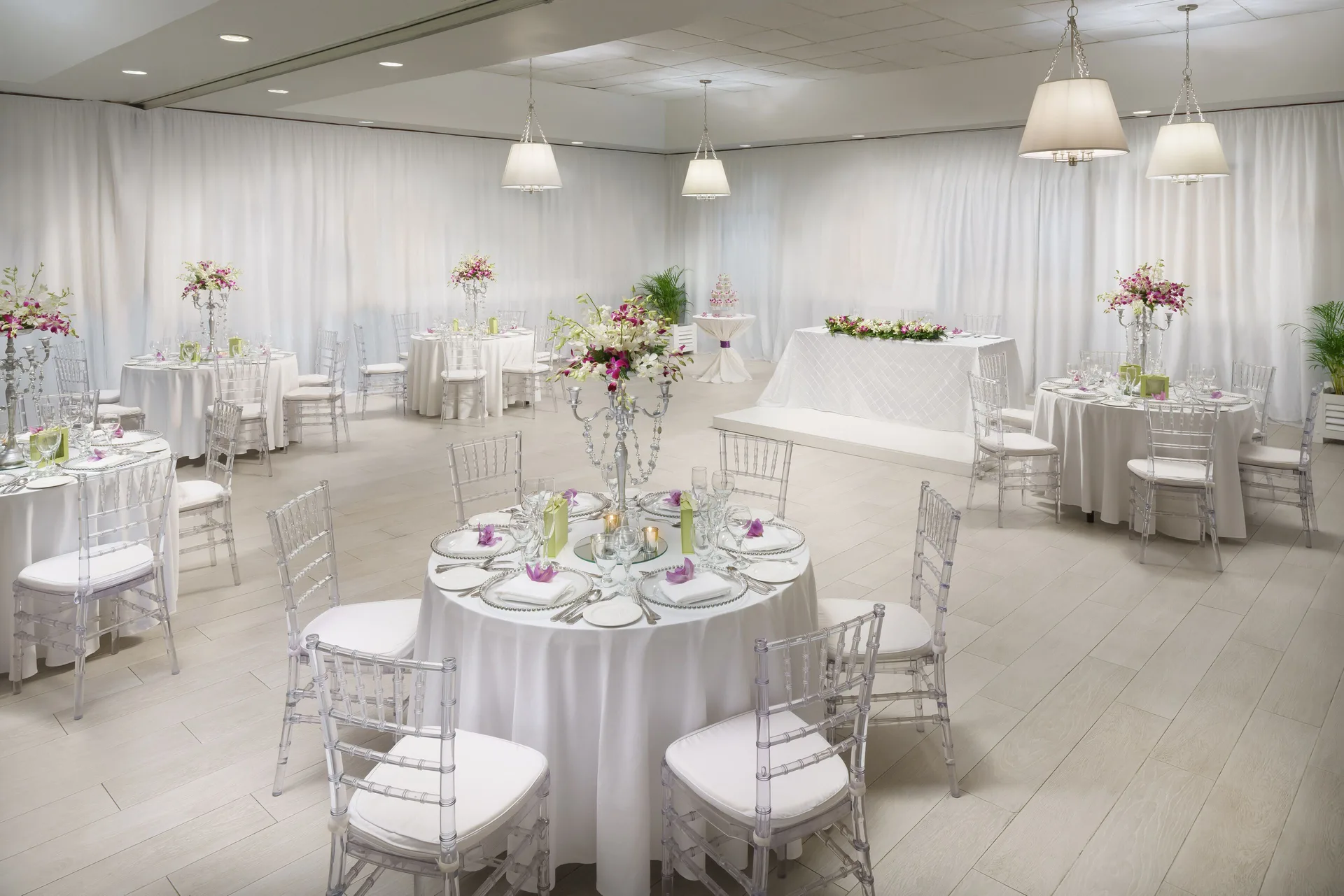 White reception room with round tables and floral centerpieces at Couples Sans Souci.