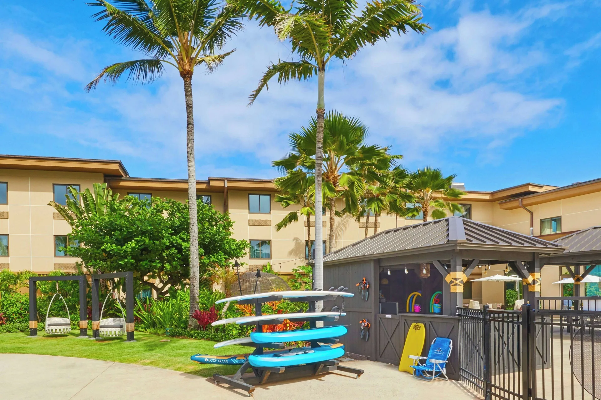 Surfboards, palms, and poolside cabana area at Courtyard Oahu North Shore.