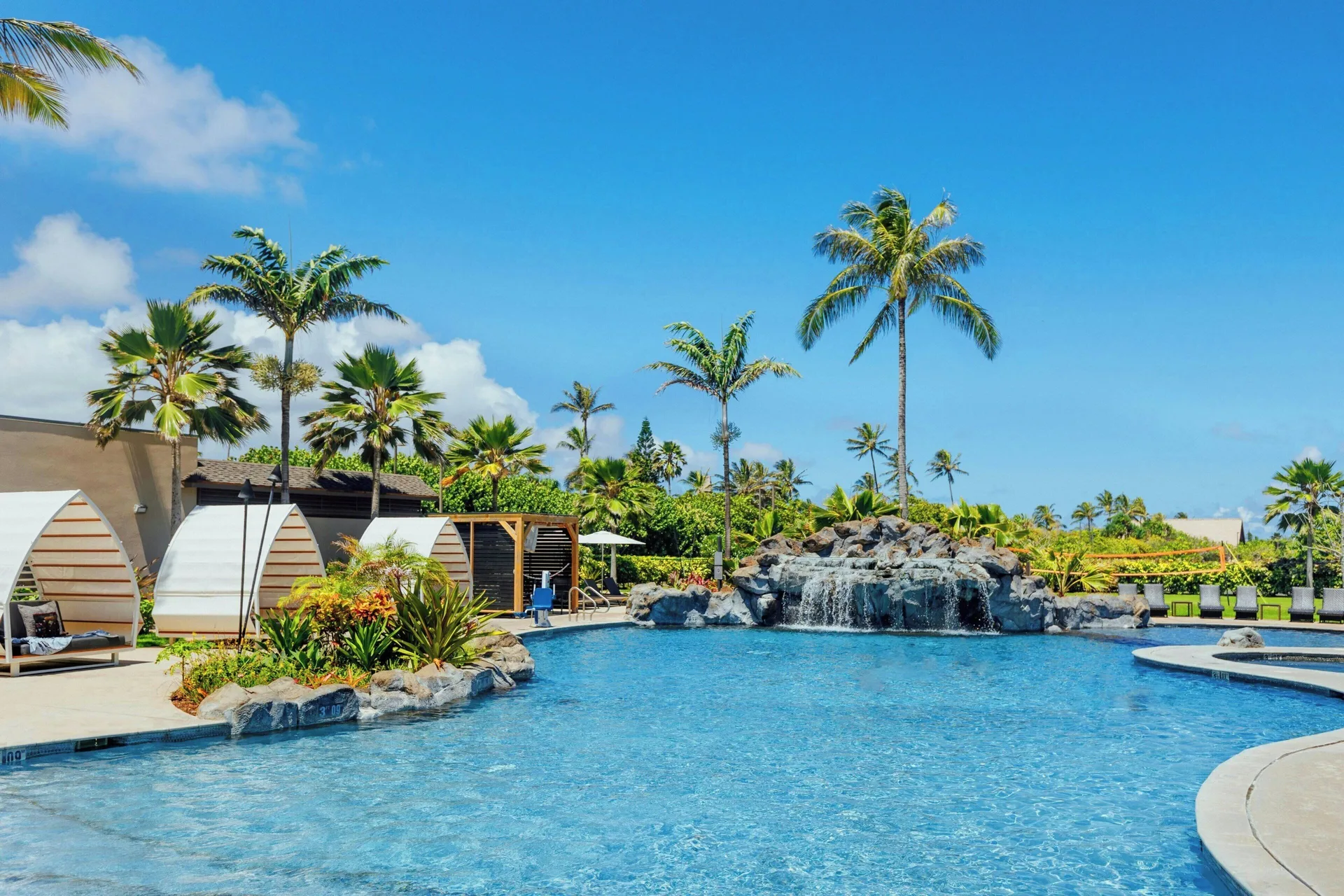 Resort pool with waterfall, palms, and cabanas at Courtyard Oahu North Shore.