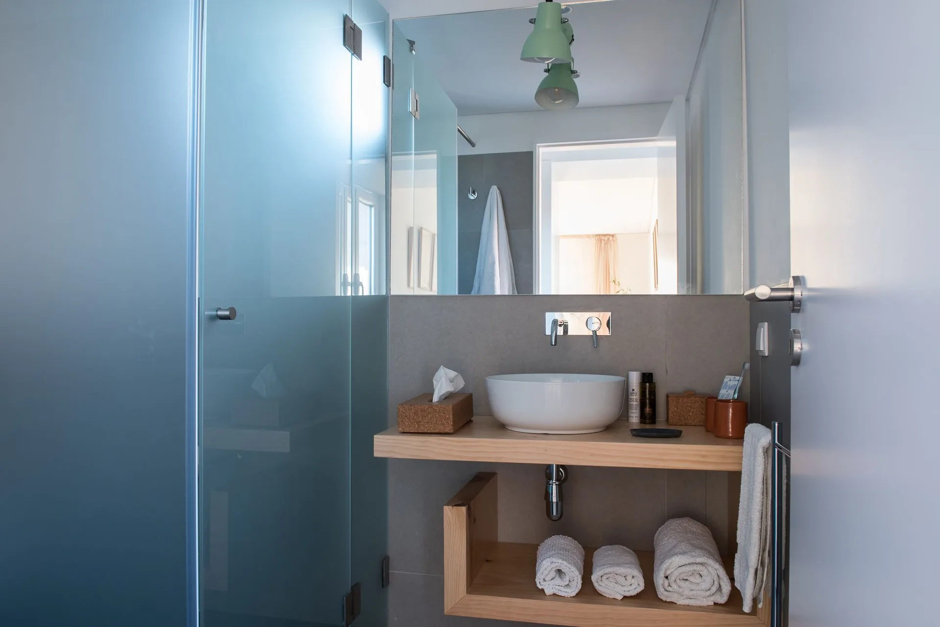 Studio bathroom vanity with glass shower and towels at Craveiral Farmhouse.