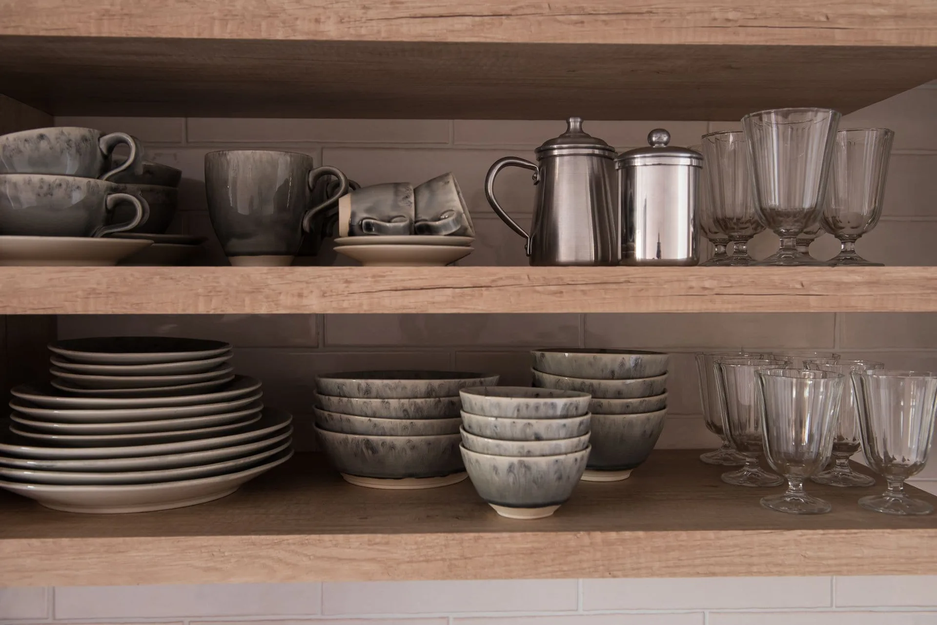 Studio kitchenette shelves with dishes and glasses at Craveiral Farmhouse.