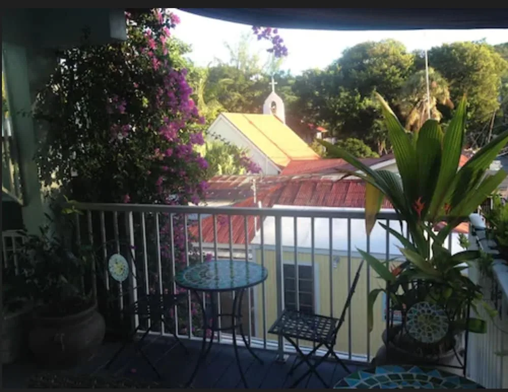 Balcony seating with plants and rooftops beyond at Cruz Bay Boutique Hotel.