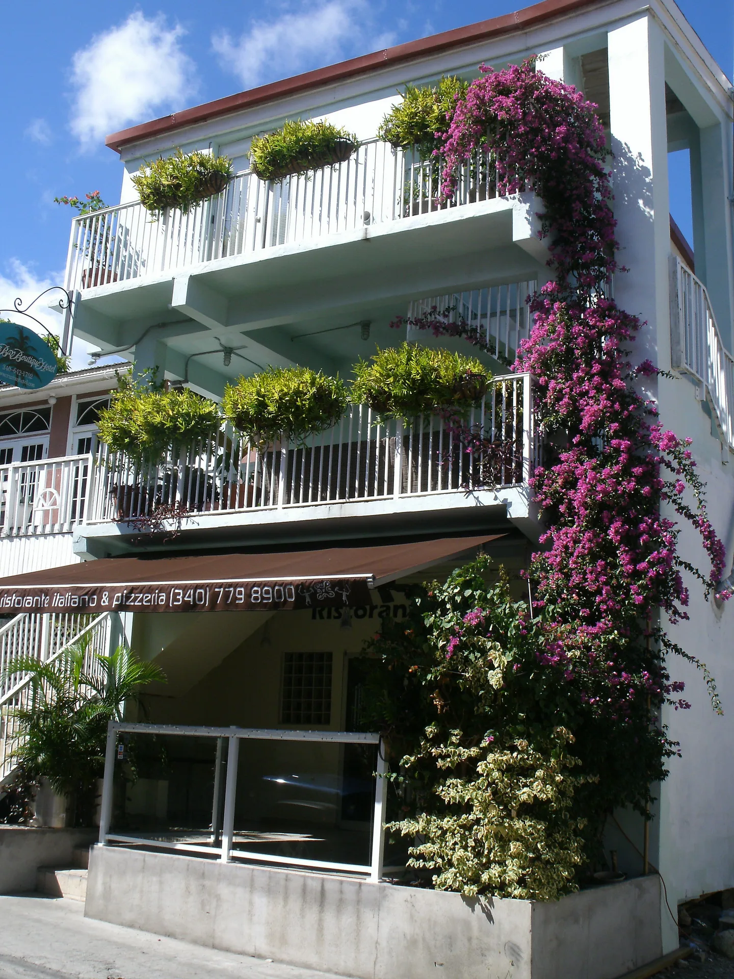 Street-facing hotel exterior with balconies and bougainvillea at Cruz Bay Boutique Hotel.