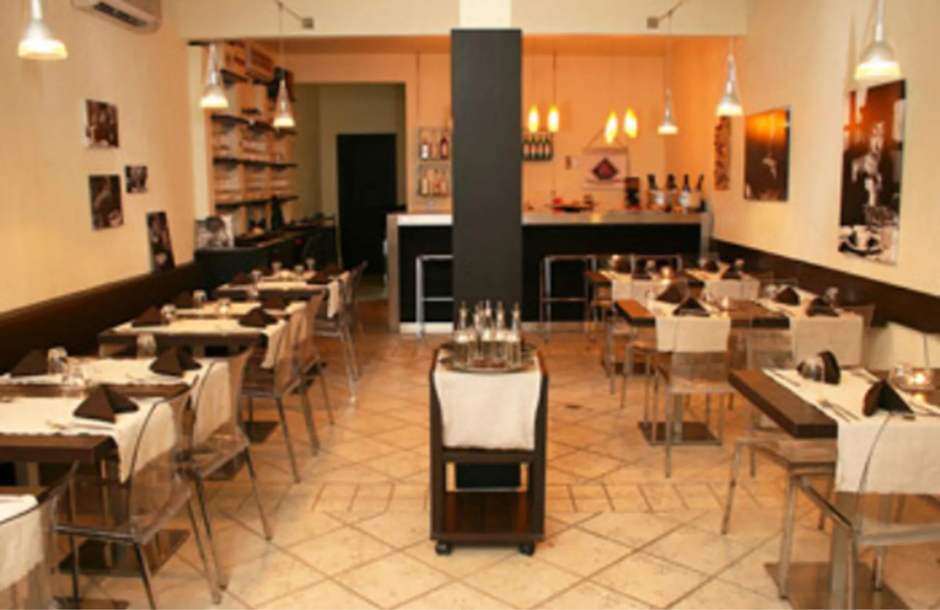 Dining room with set tables, pendant lights, and a bar at Cruz Bay Boutique Hotel.