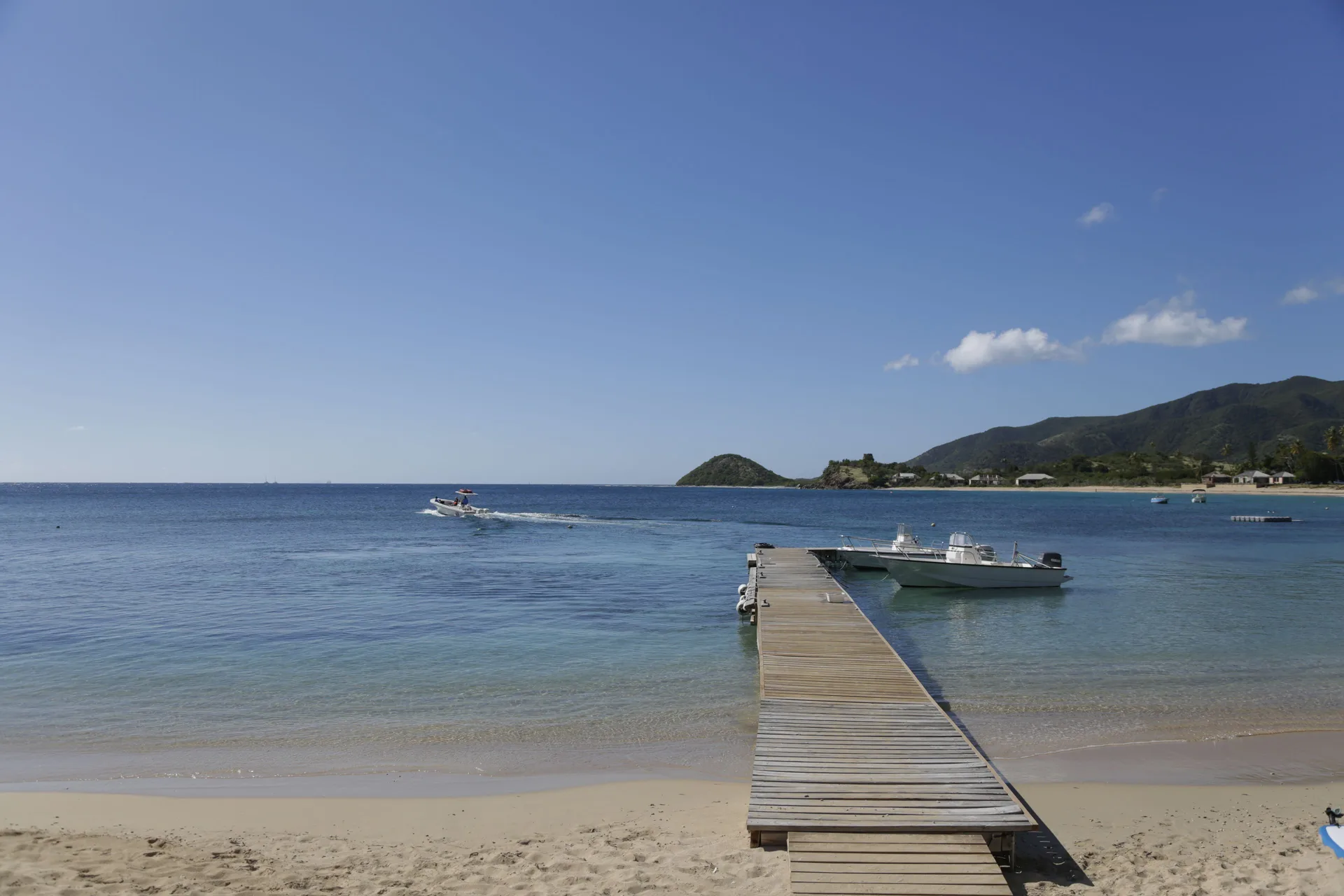 A wooden pier extends from the beach into calm water at Curtain Bluff Resort.