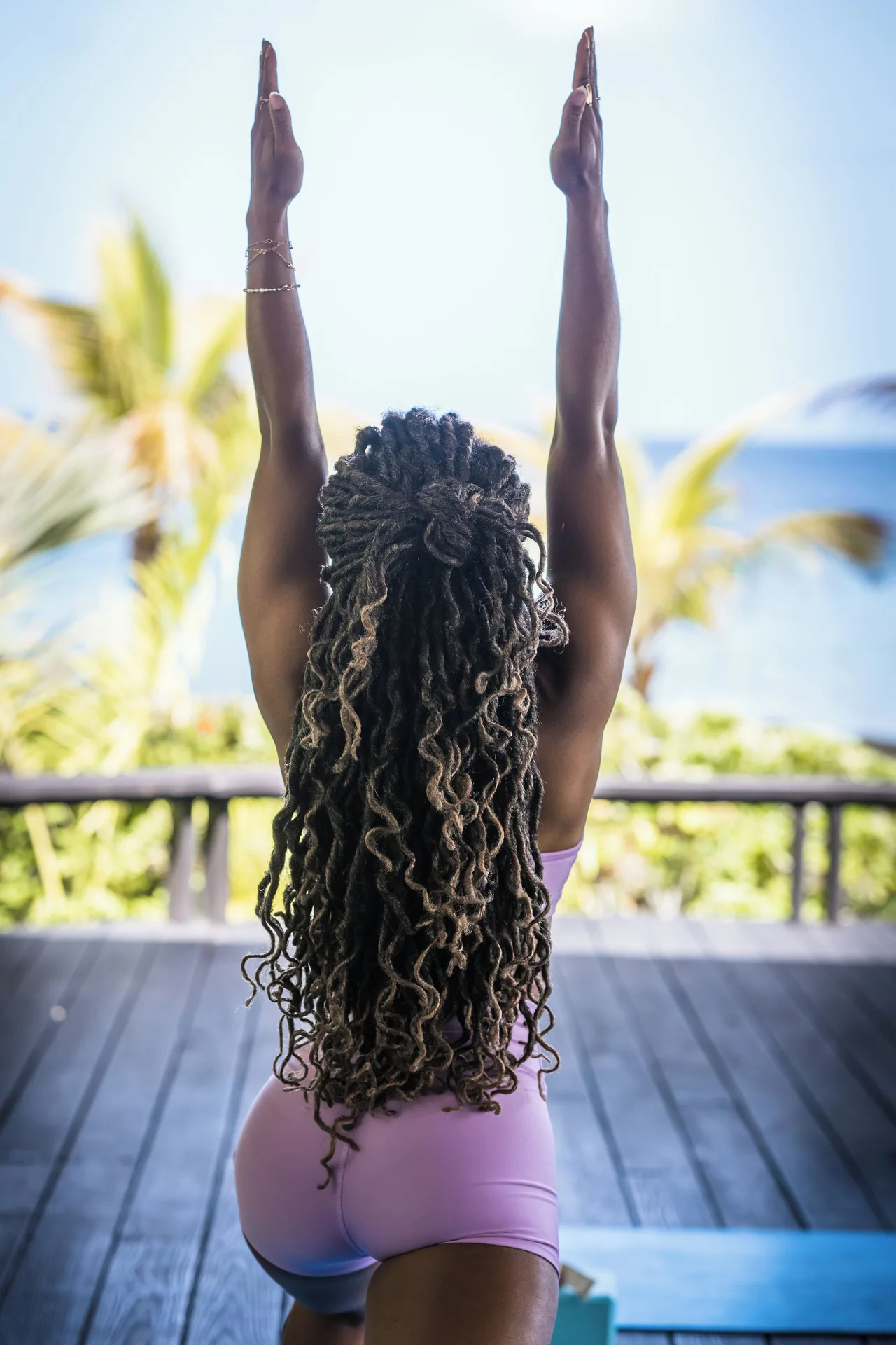 A guest practices yoga on a shaded deck overlooking the sea at Curtain Bluff Resort.