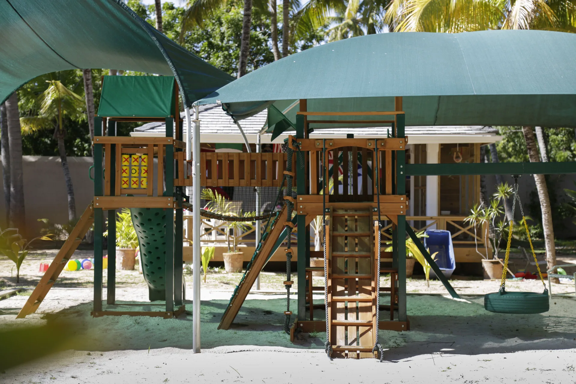 A shaded children's play structure stands in sand at Curtain Bluff Resort.