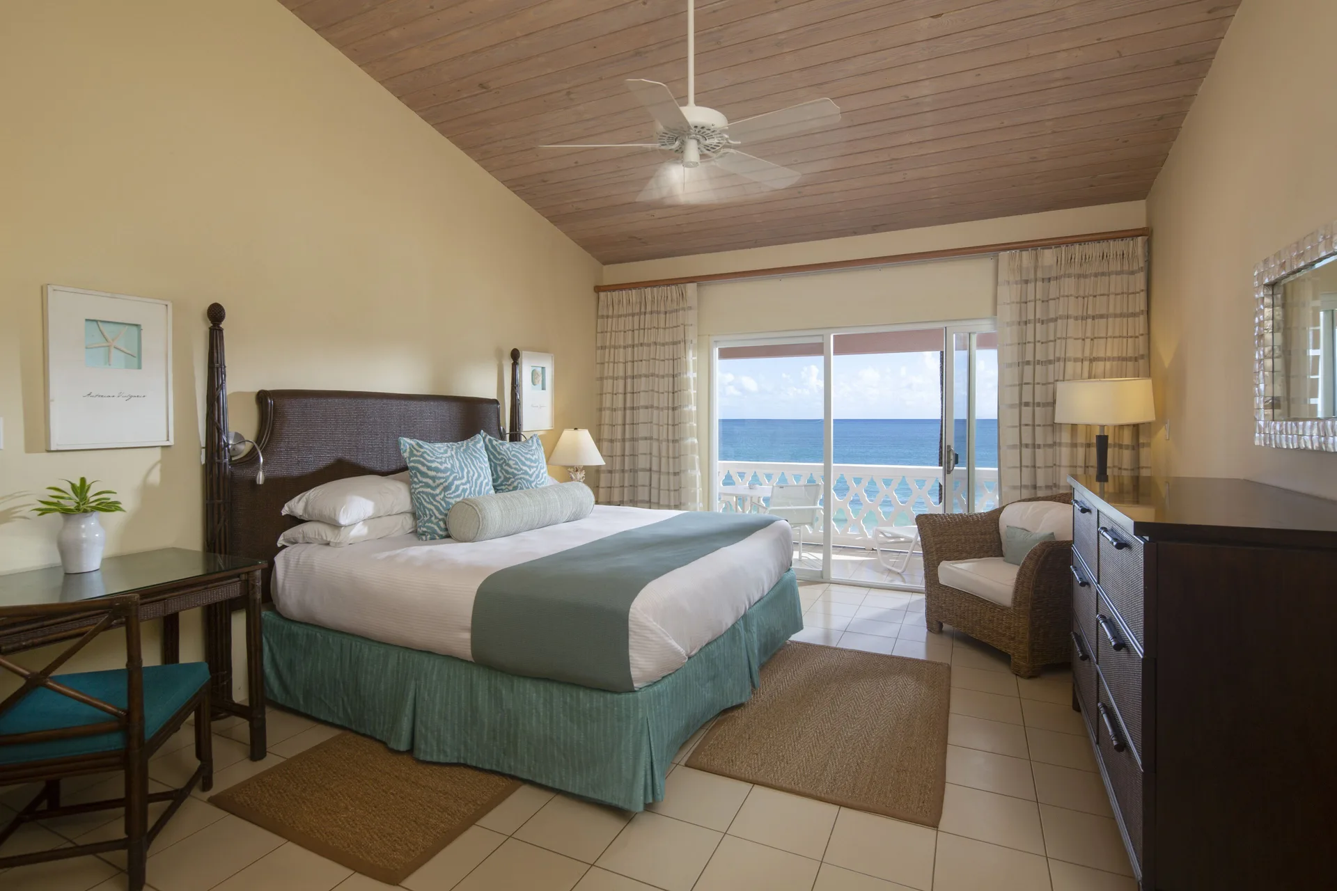 Deluxe Room Beach View bedroom with king bed and ocean-facing balcony at Curtain Bluff Resort.