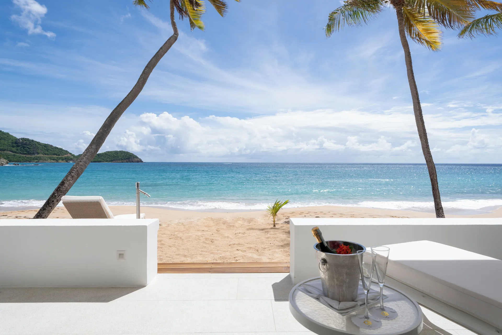 Beachfront terrace with lounge seating and ocean view at Curtain Bluff Resort.