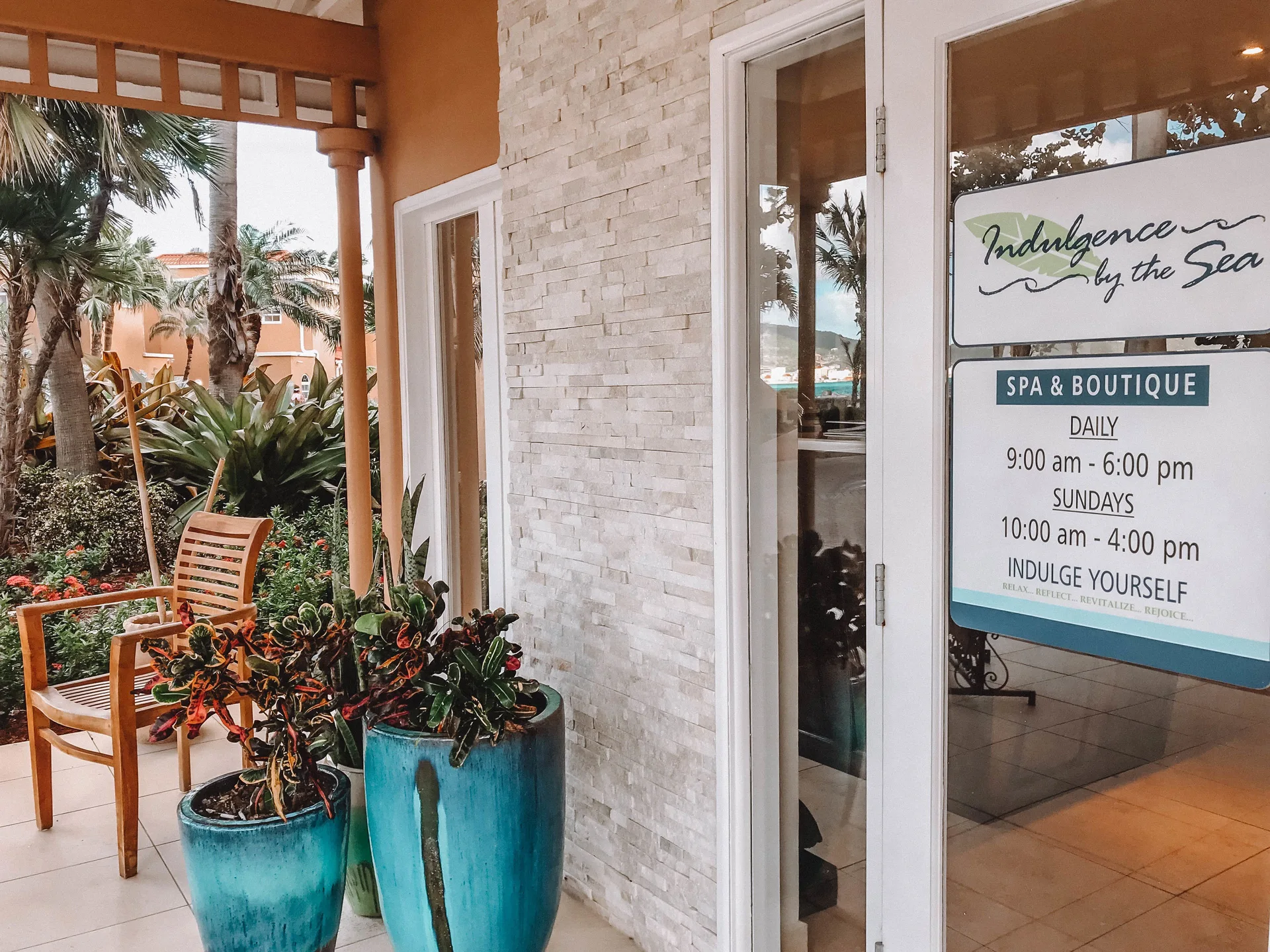 Spa and boutique entrance sign beside potted plants at Divi Little Bay Beach Resort.