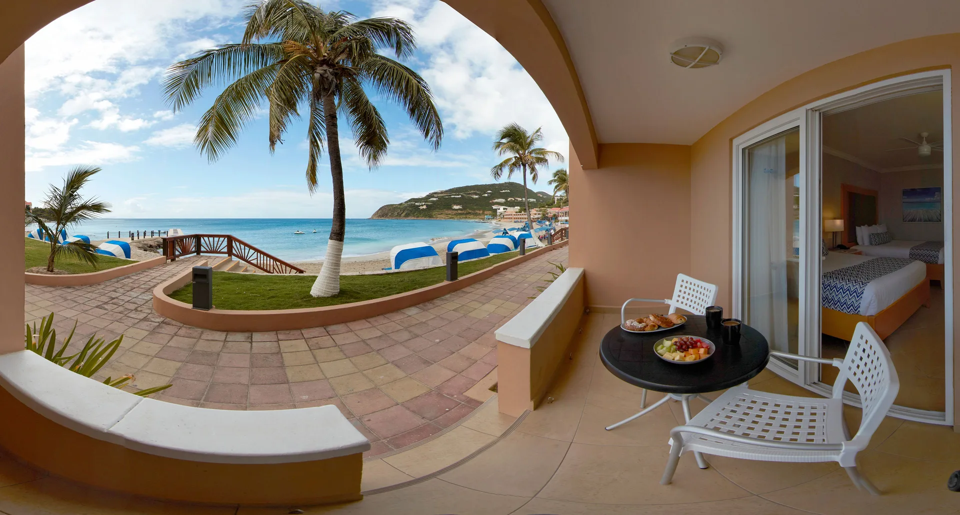 Beachside room patio and king bed beside the beach at Divi Little Bay Beach Resort.