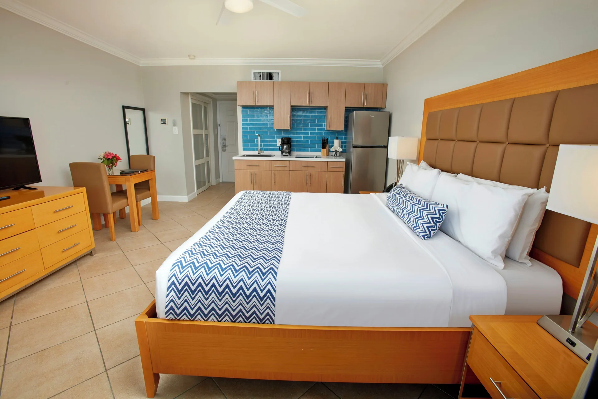 Studio Suite king bed with kitchenette and TV dresser at Divi Little Bay Beach Resort.