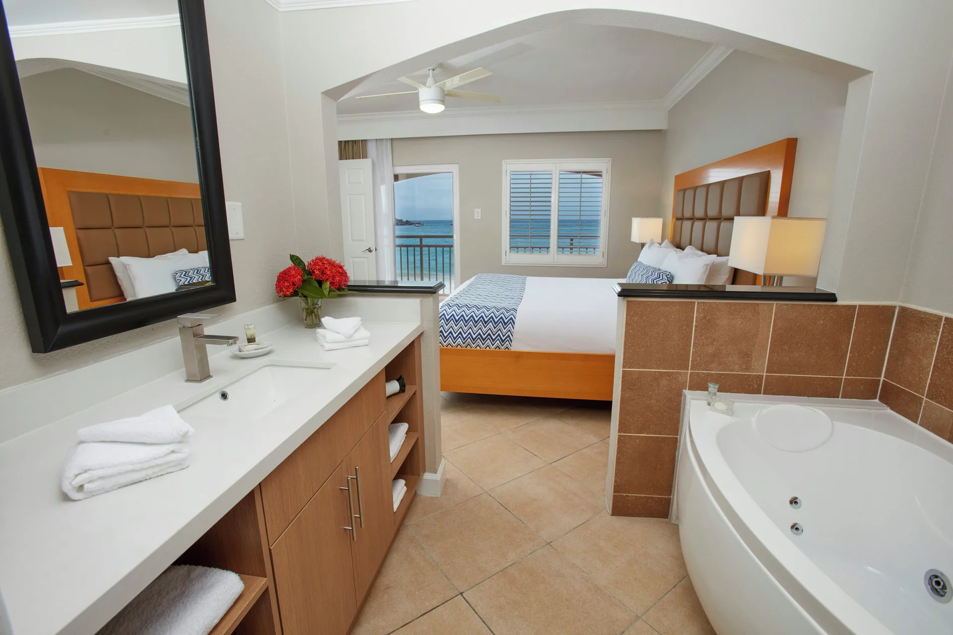 One Bedroom Suite king bed and open bathroom with soaking tub at Divi Little Bay Beach Resort.