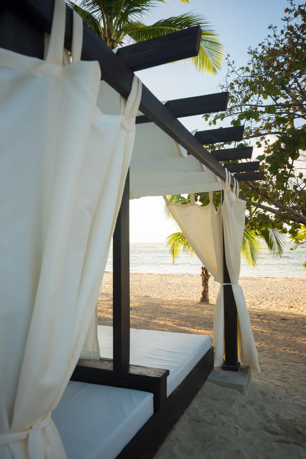 Beach cabana with white curtains facing the sea at Emotions by Hodelpa Puerto Plata.