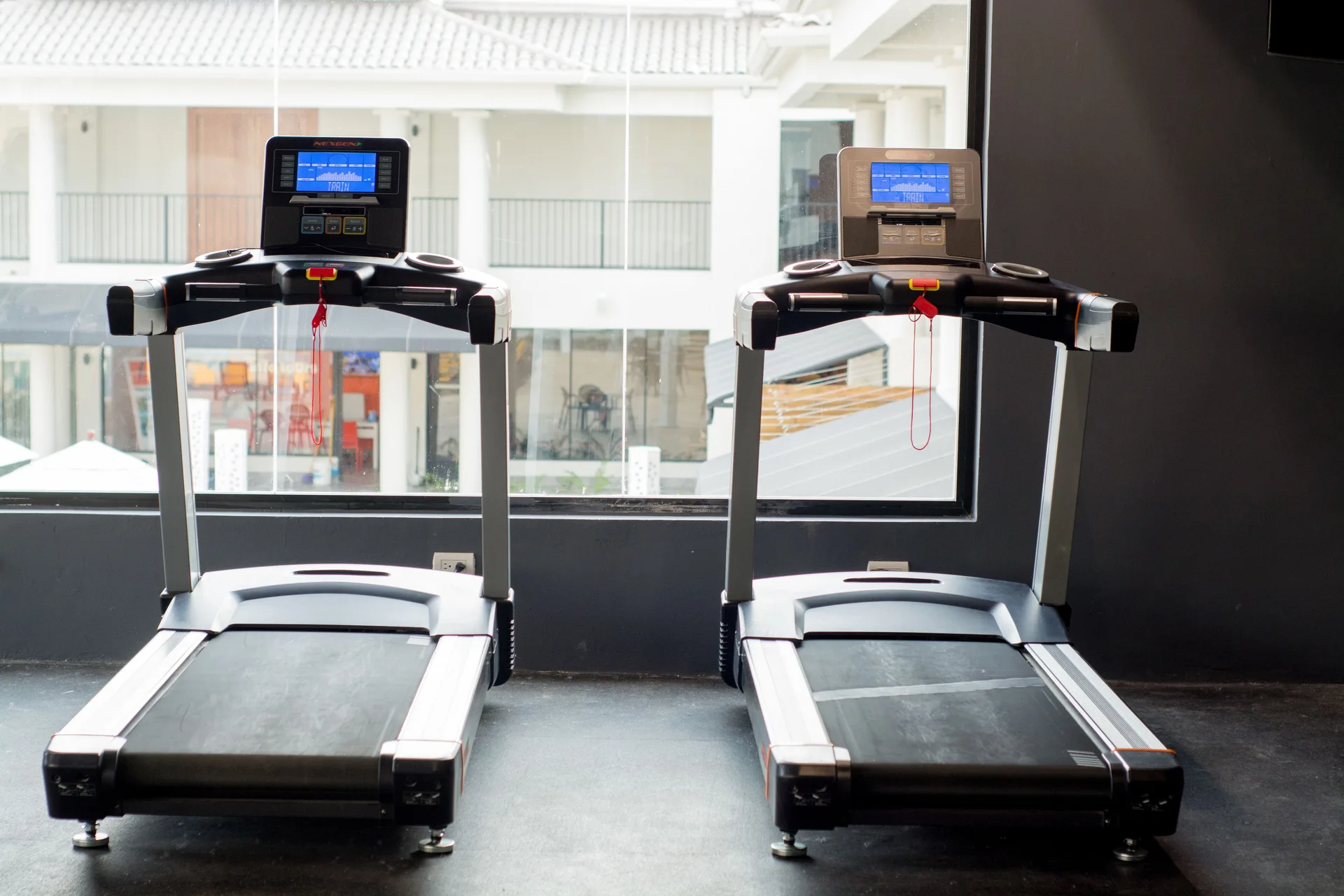 Two treadmills facing windows in the fitness room at Emotions by Hodelpa Puerto Plata.