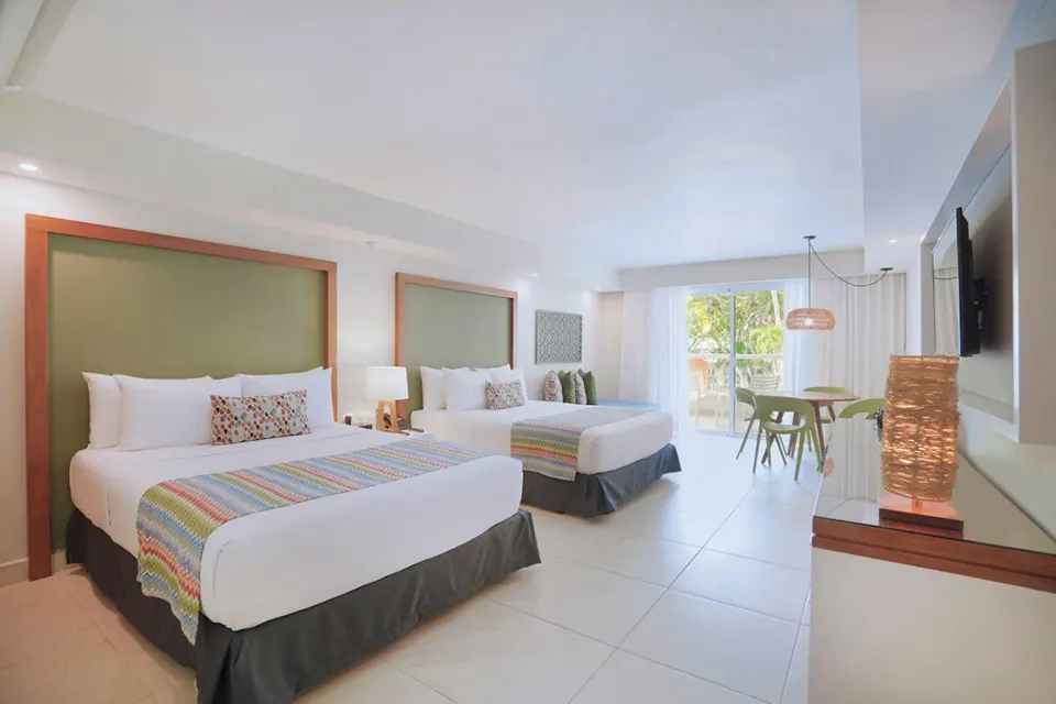 Family Deluxe room with two beds and balcony seating at Emotions by Hodelpa Puerto Plata.
