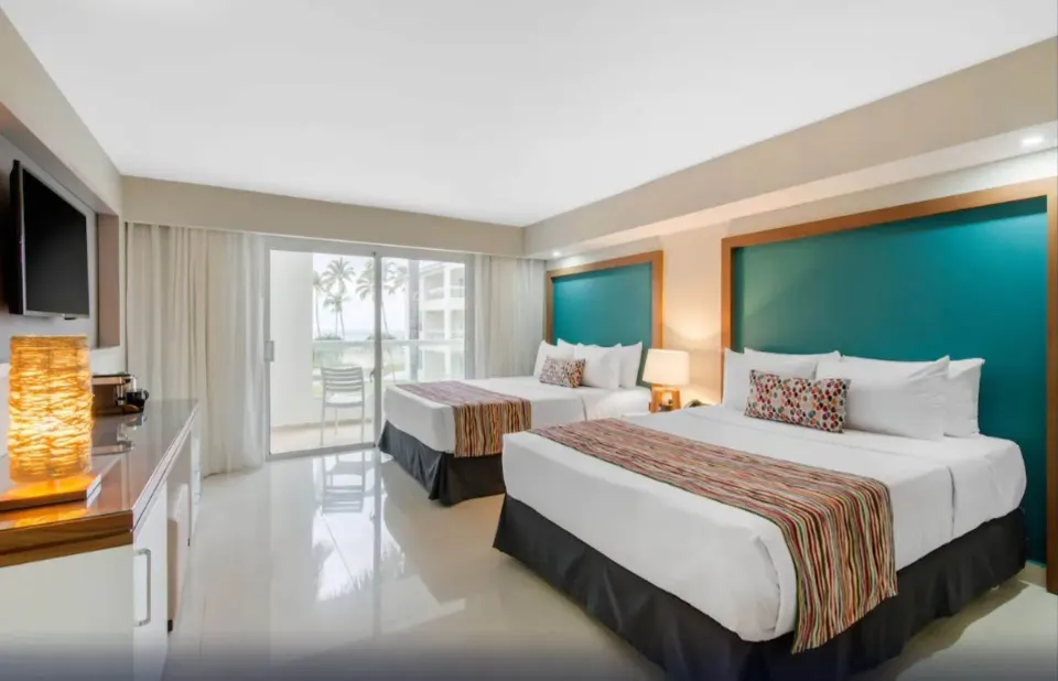 Family Deluxe room with teal headboards and balcony at Emotions by Hodelpa Puerto Plata.