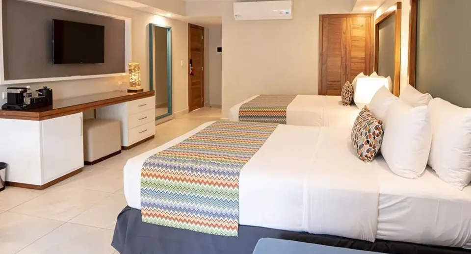 Family Deluxe room beds, TV, and storage area at Emotions by Hodelpa Puerto Plata.