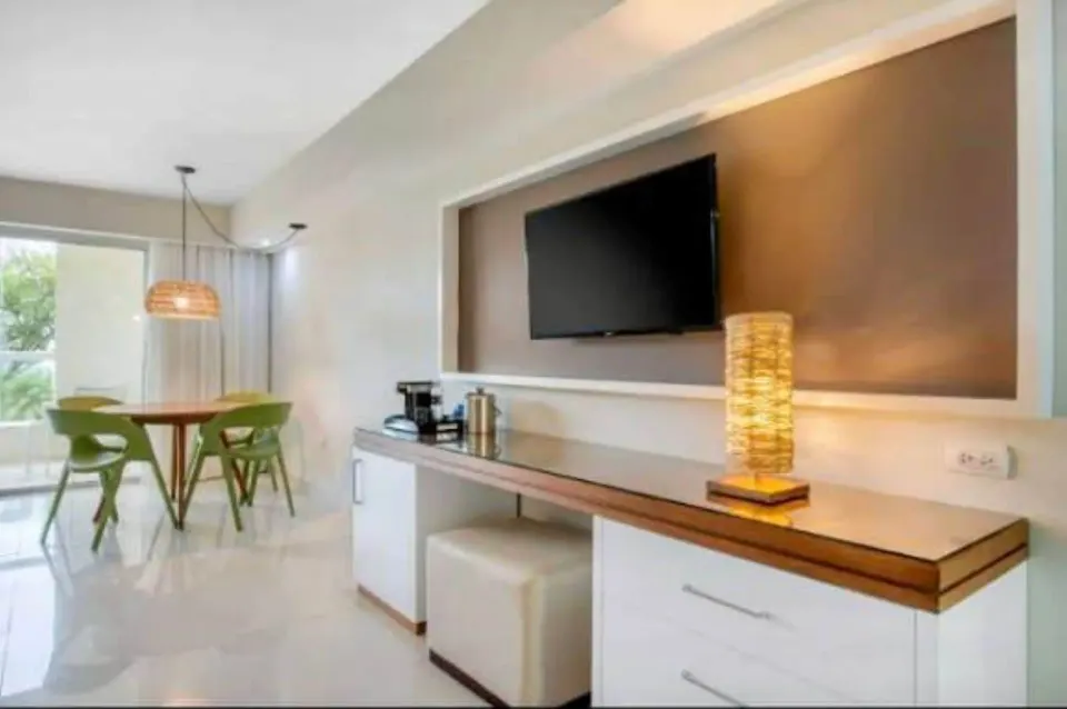 Superior Standard room desk and dining area at Emotions by Hodelpa Puerto Plata with TV and green chairs.