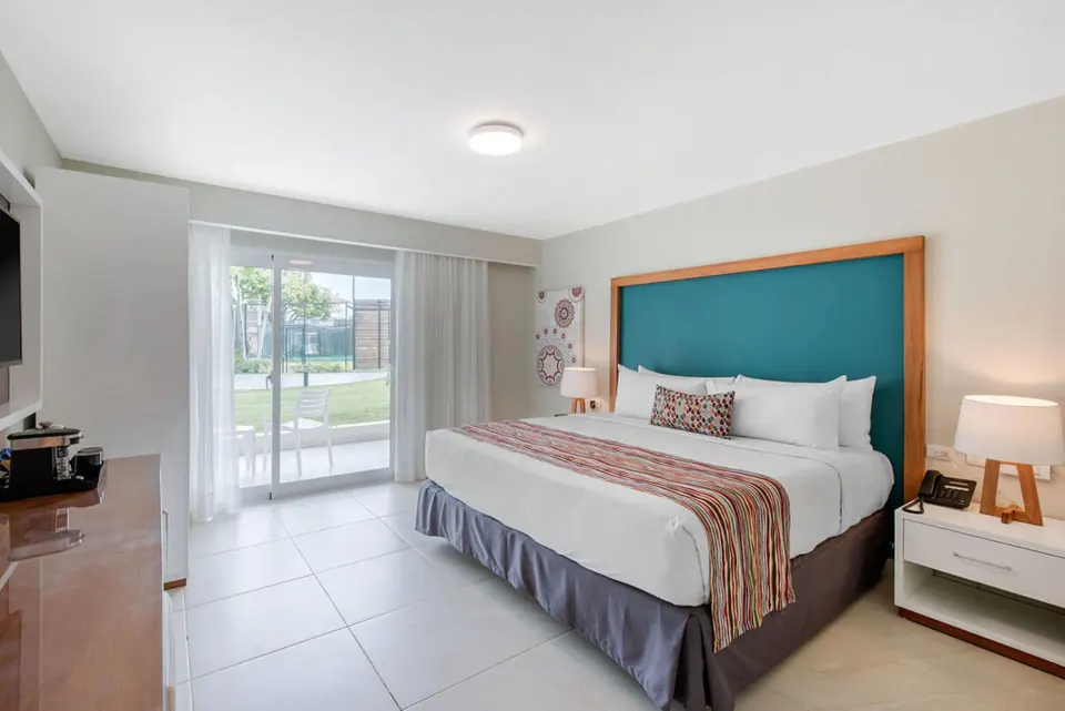 Superior Standard king bed room at Emotions by Hodelpa Puerto Plata with patio doors and turquoise headboard.