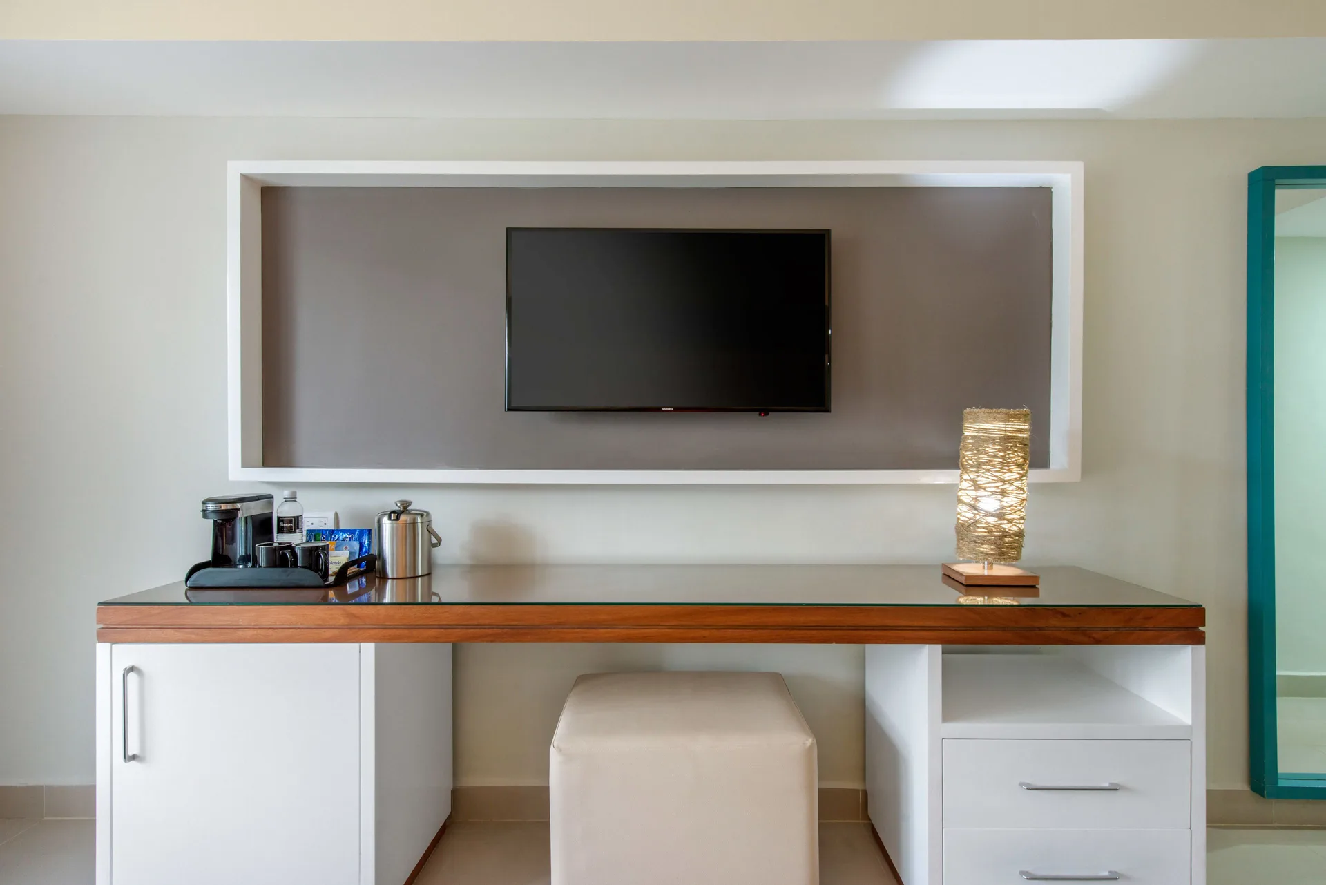 Superior Standard room media wall at Emotions by Hodelpa Puerto Plata with TV, desk, lamp, and refreshment area.