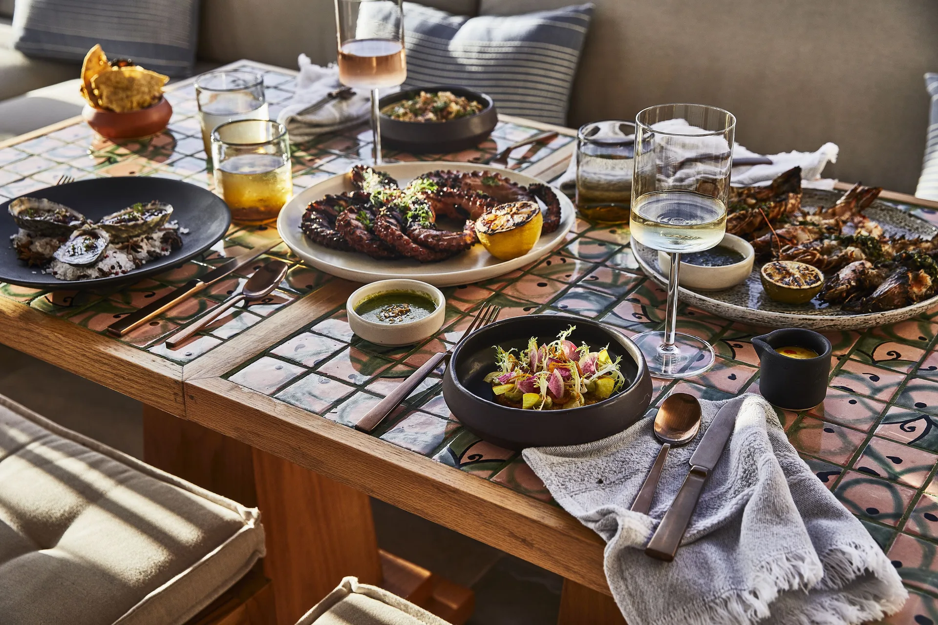 Seafood and grilled dishes set on a tiled table at Etéreo, Auberge Collection.