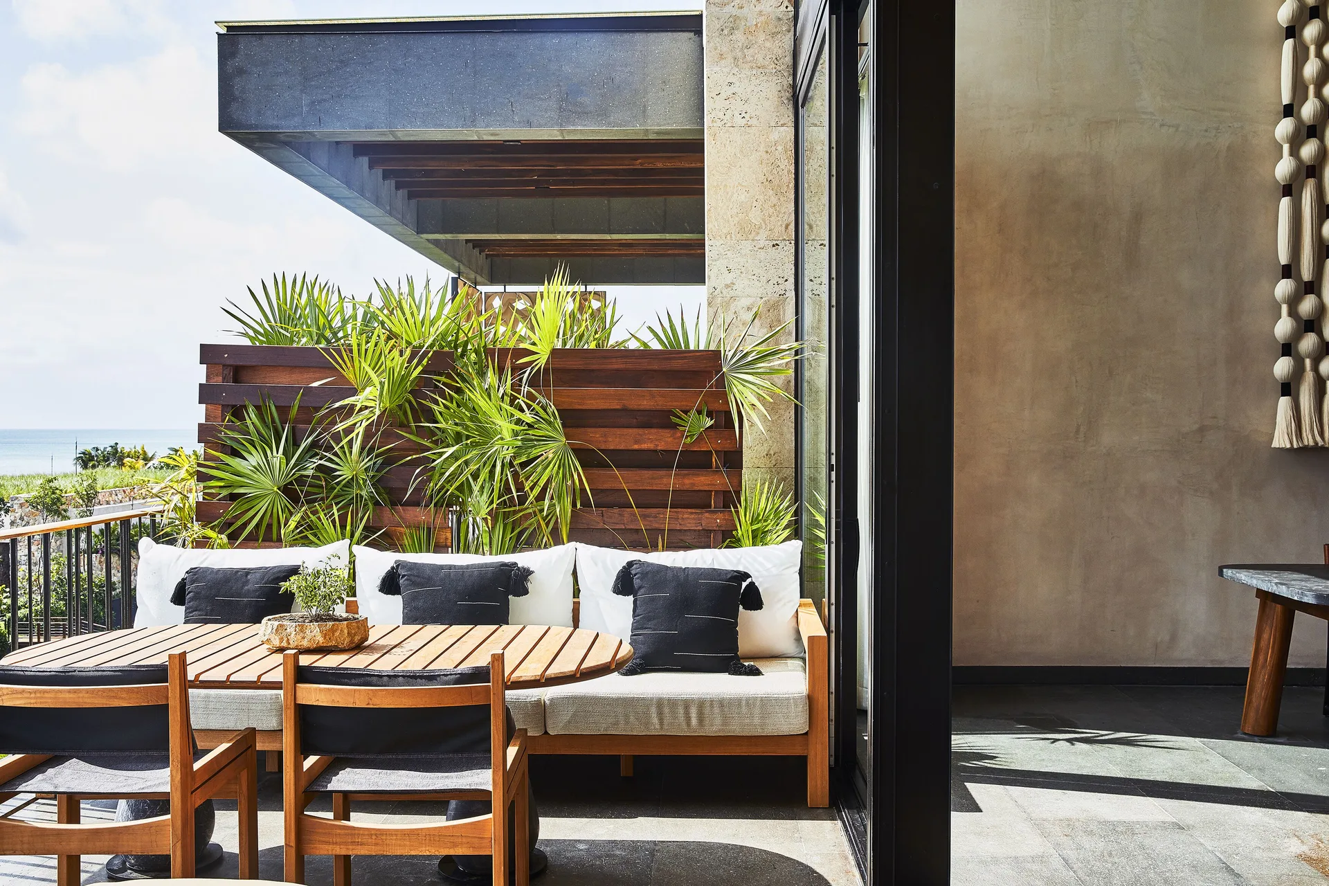Private terrace seating at Etéreo, Auberge Collection with ocean visible beyond palms.