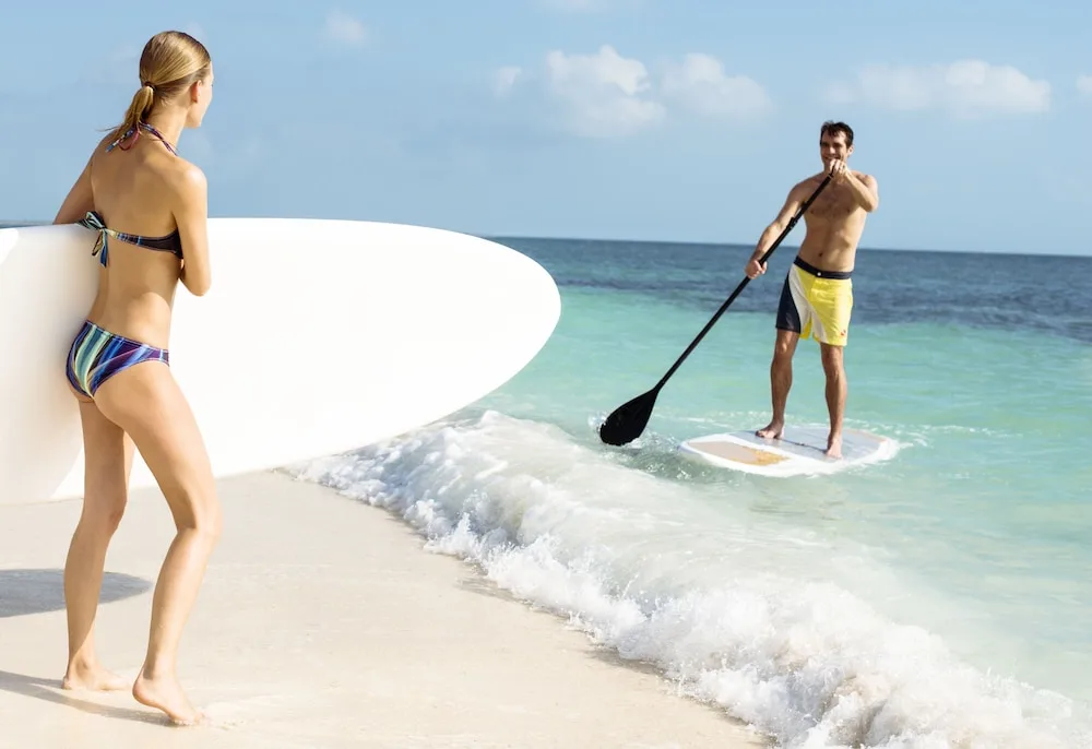 Guests paddleboarding beside the beach at Excellence Playa Mujeres.