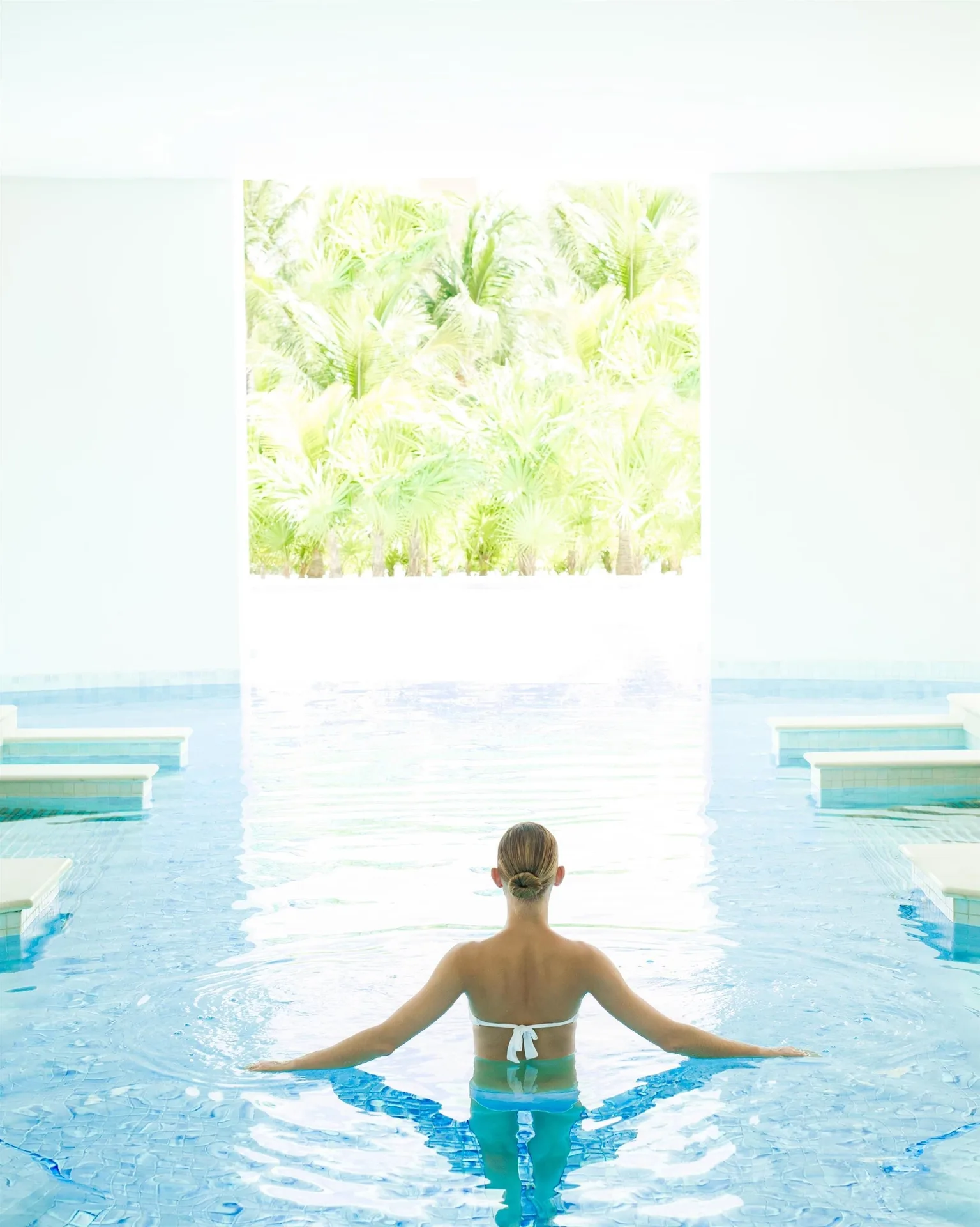 Guest standing in a bright indoor pool area at Excellence Playa Mujeres.