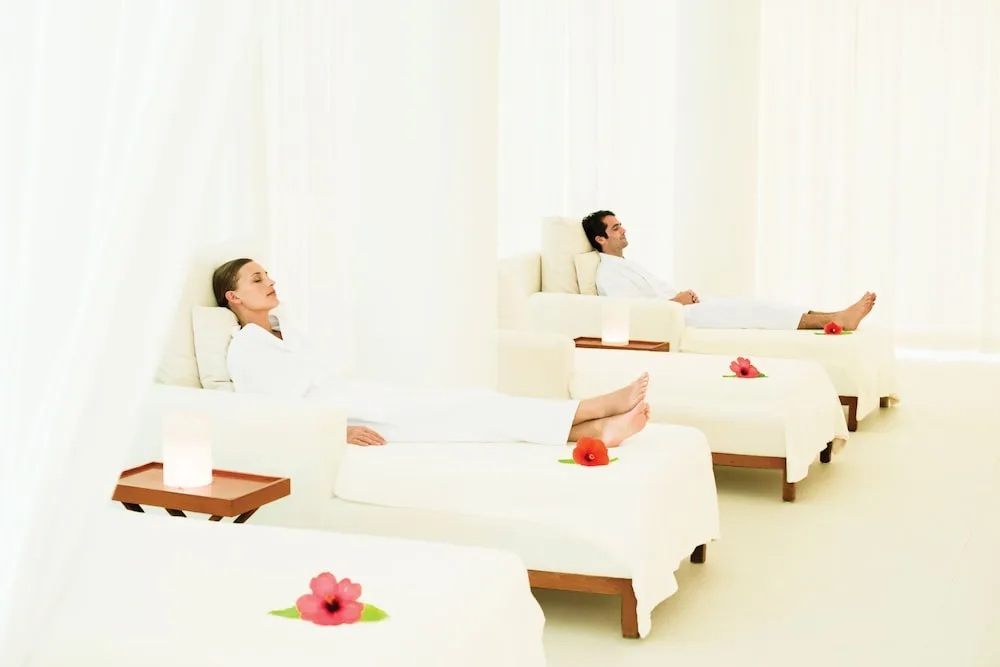 Guests resting on white spa loungers with flowers at Excellence Playa Mujeres.