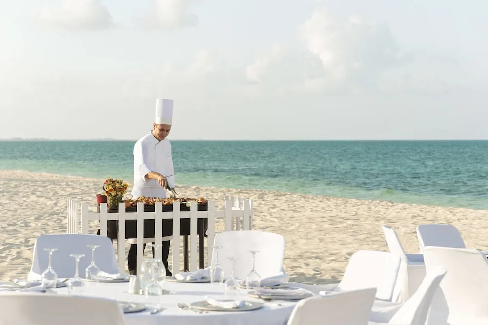 A chef grills food beside beach dining tables at Excellence Playa Mujeres.