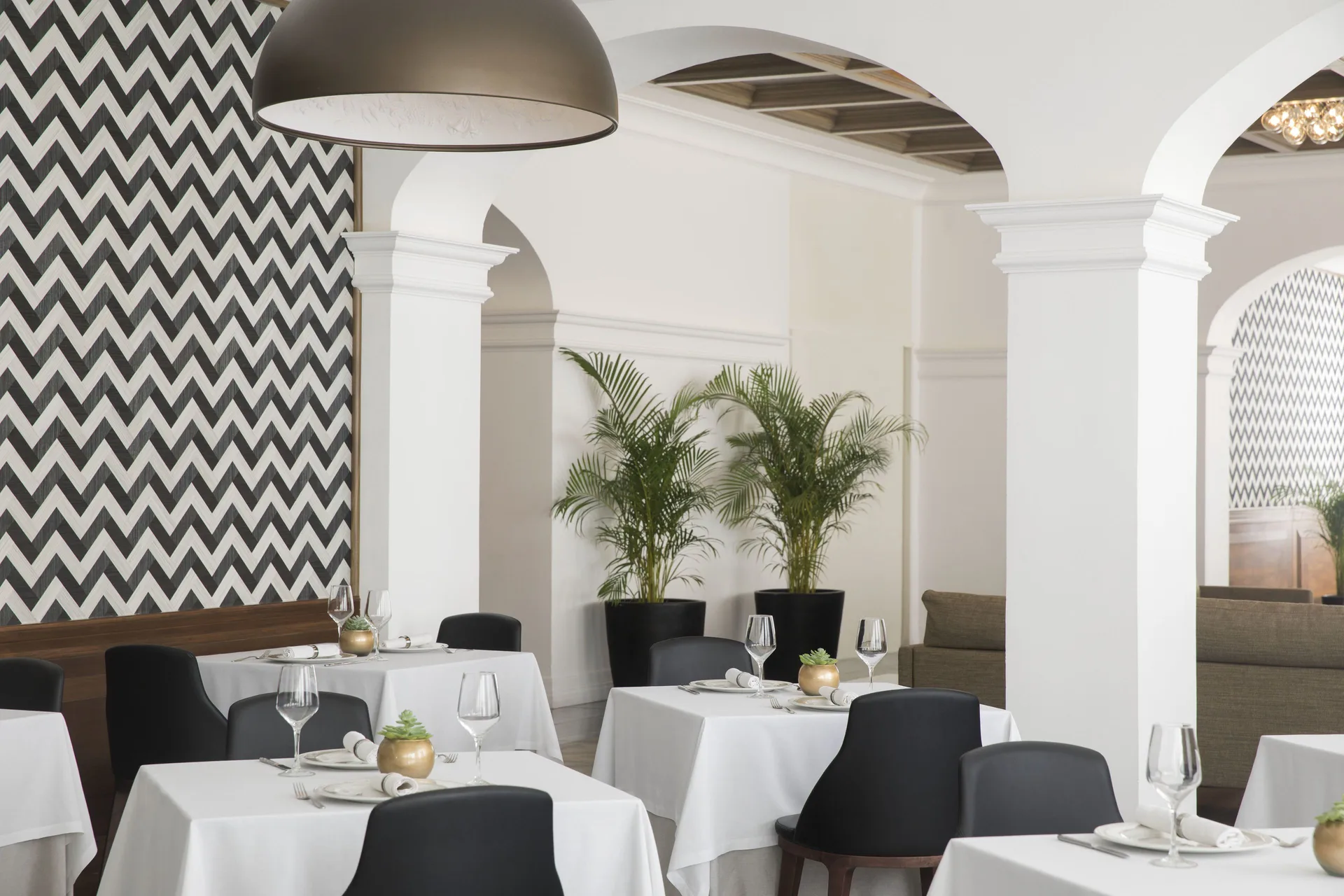 White-clothed dining tables sit beneath arches at Excellence Playa Mujeres.