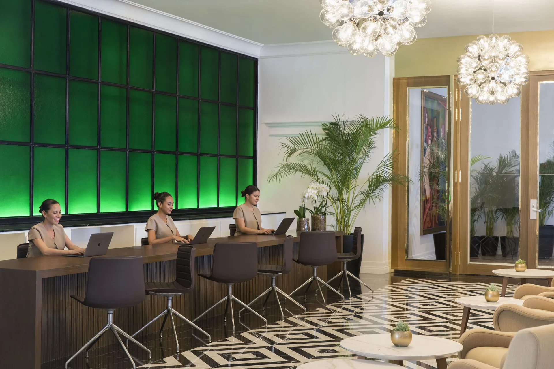 Club lounge desks with staff, green glass wall, and seating at Excellence Playa Mujeres.