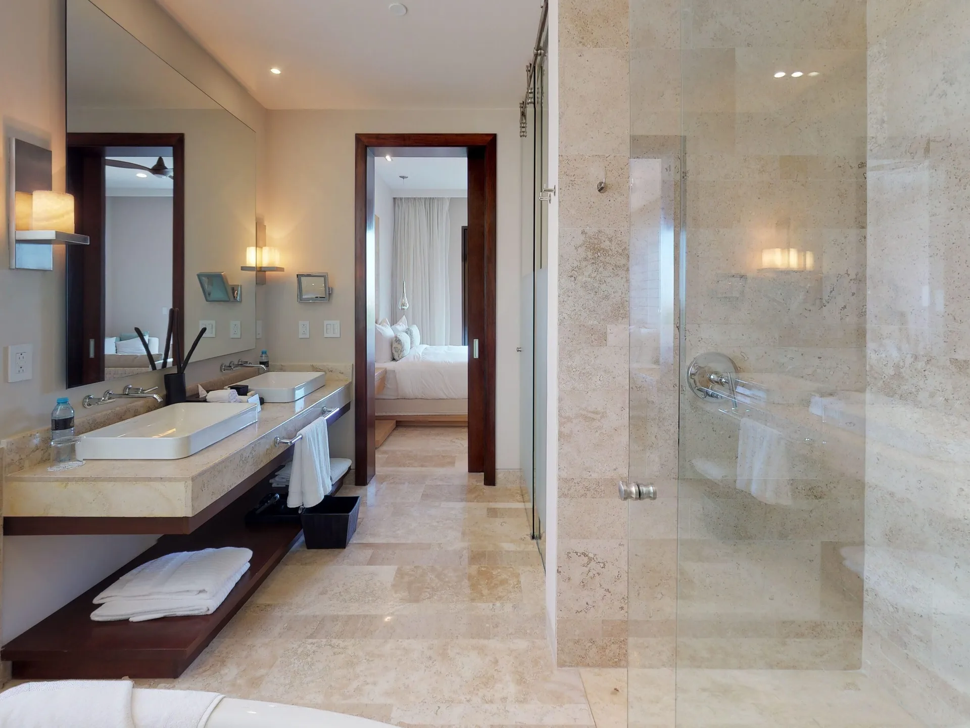 Stone bathroom with double vanity and glass shower at Fairmont Heritage Place Mayakoba.