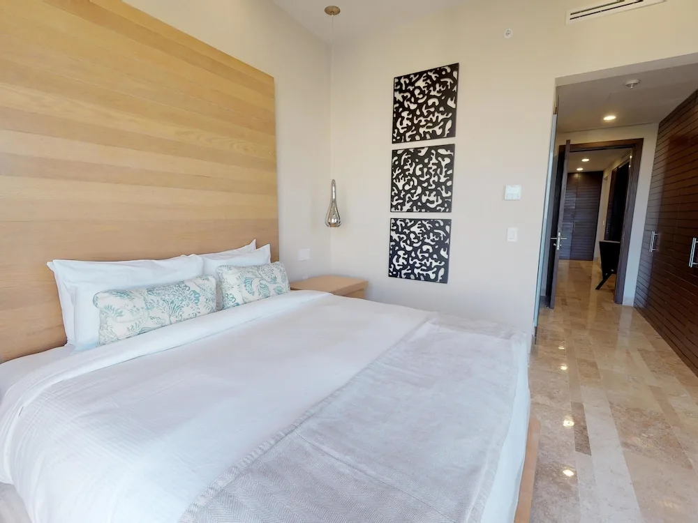 Bedroom with king bed and wood headboard at Fairmont Heritage Place Mayakoba.