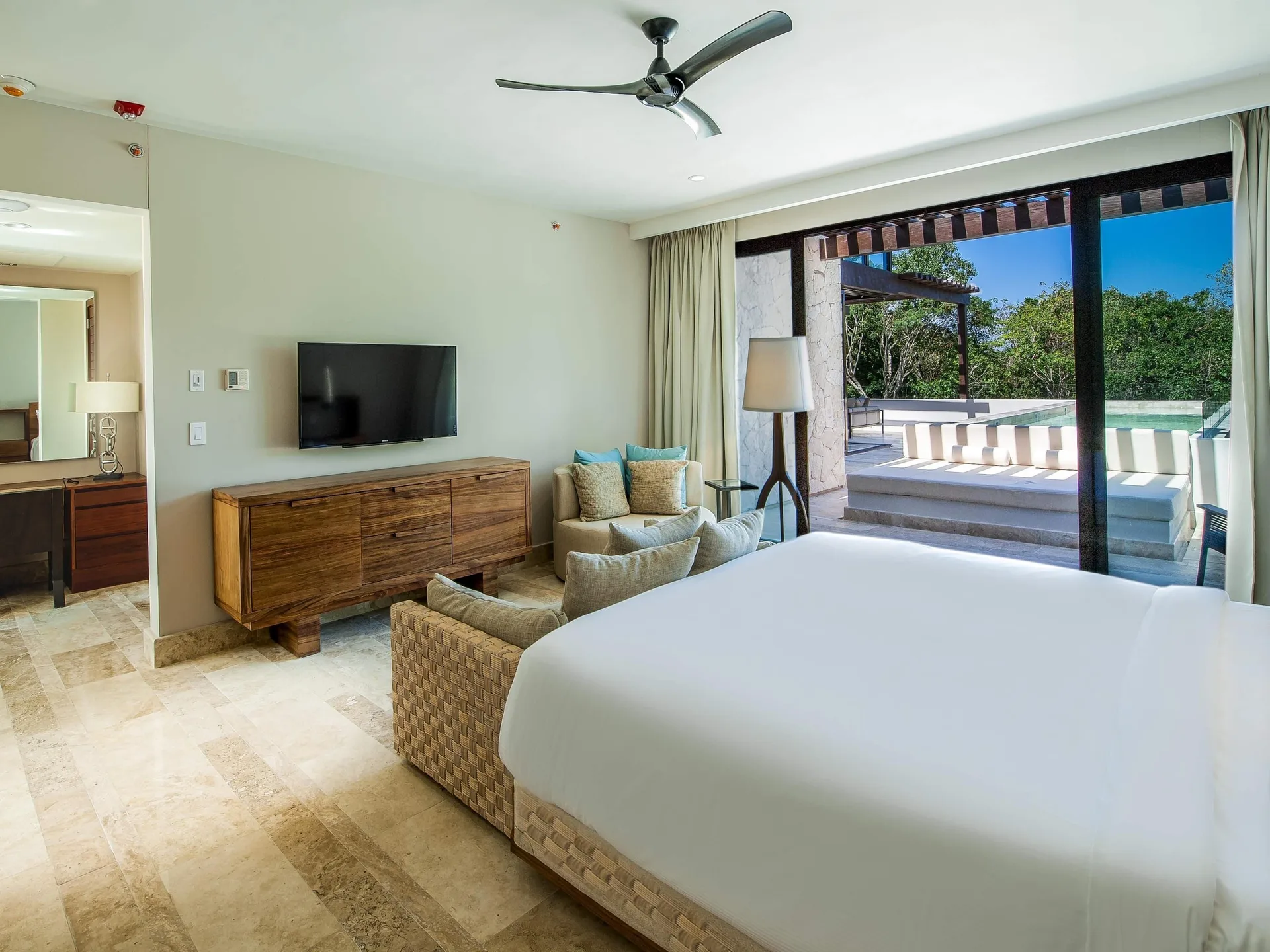 Guest room with king bed, TV, seating, and terrace at Fairmont Heritage Place Mayakoba.