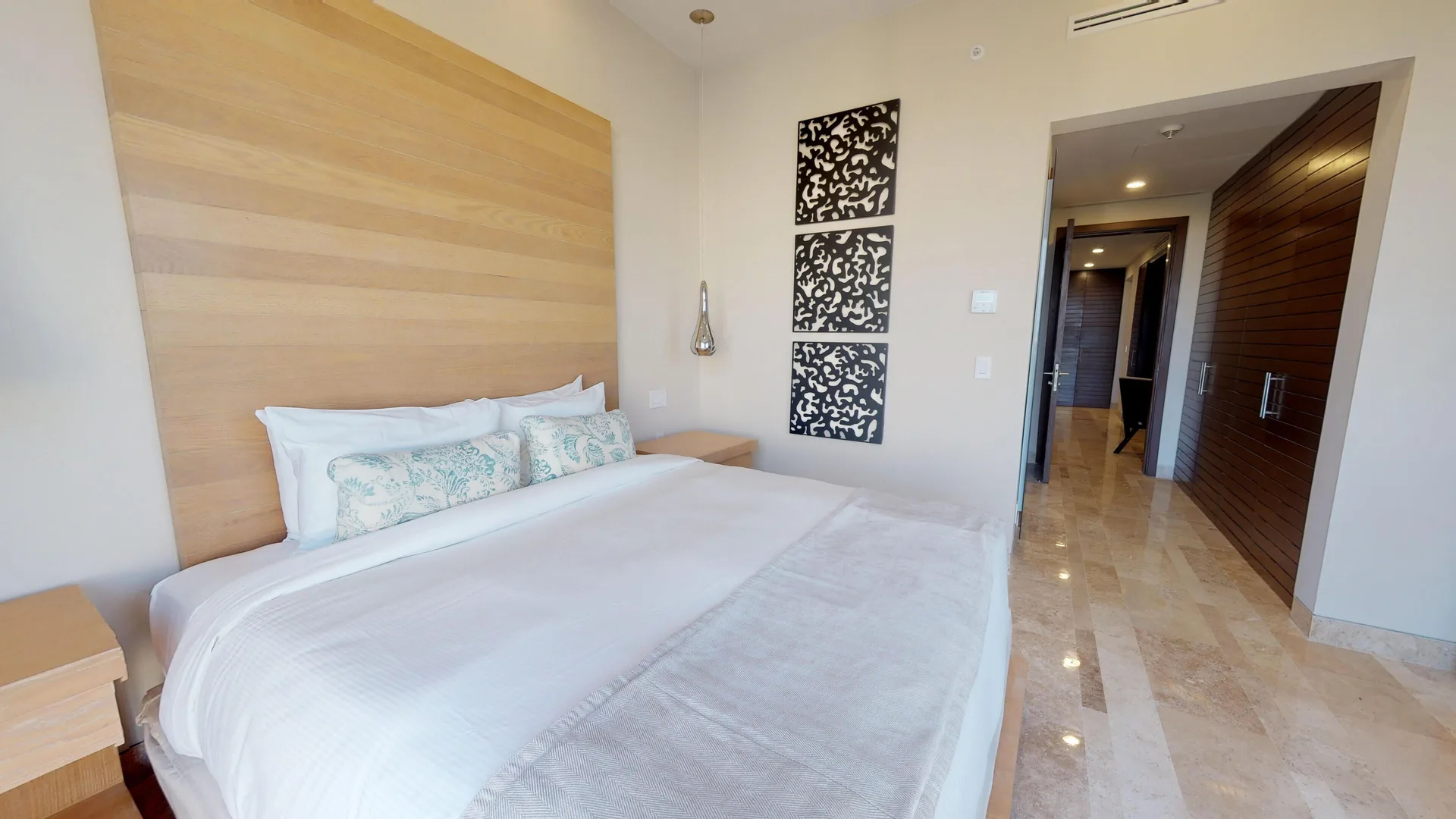 King-bed guest room with hallway and decorative wall panels at Fairmont Heritage Place Mayakoba.