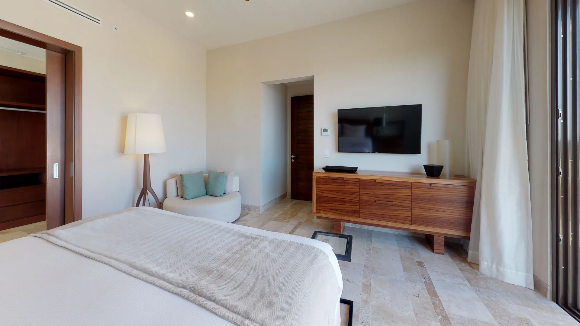 King-bed guest room with lounge chair and wood media console at Fairmont Heritage Place Mayakoba.
