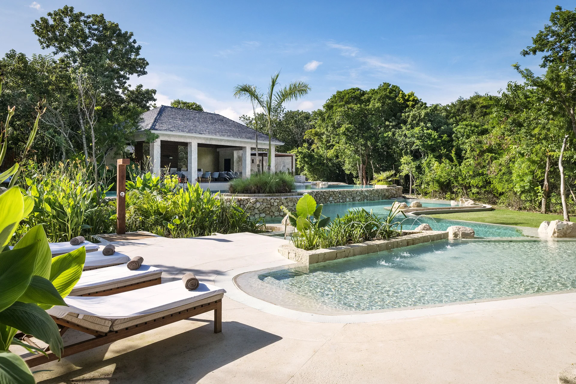 Resort pool with loungers and lush greenery at Fairmont Heritage Place Mayakoba.