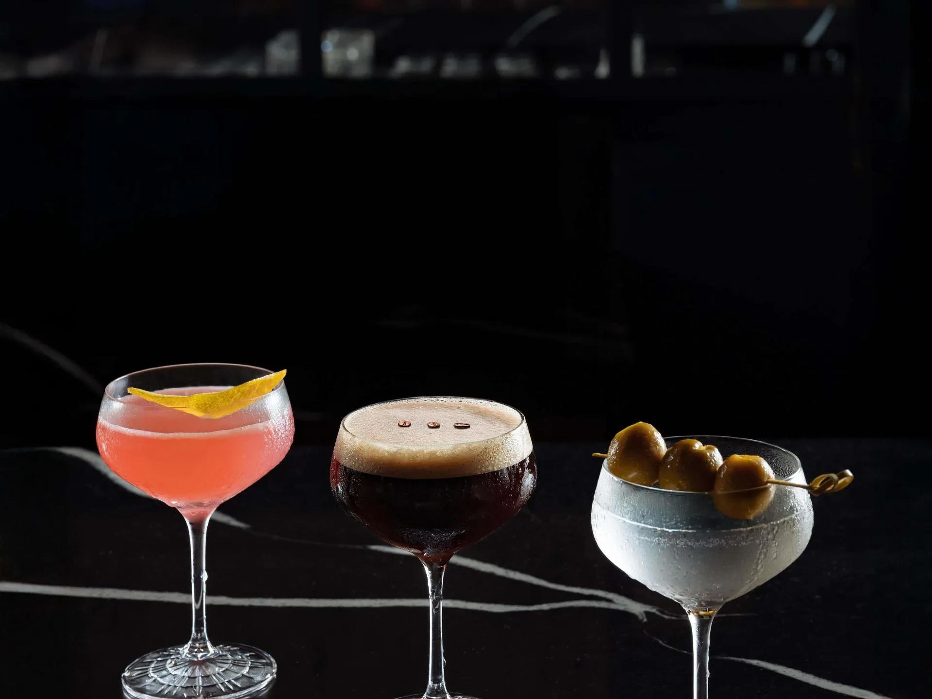 Three cocktails on a dark bar top at Fairmont Heritage Place Mayakoba.