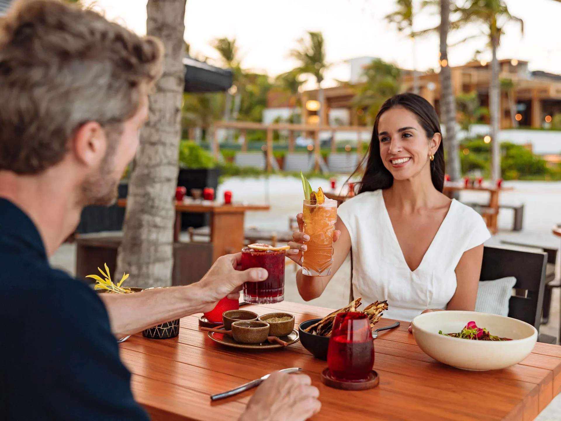 Guests toast cocktails over dinner outdoors at Fairmont Heritage Place Mayakoba.
