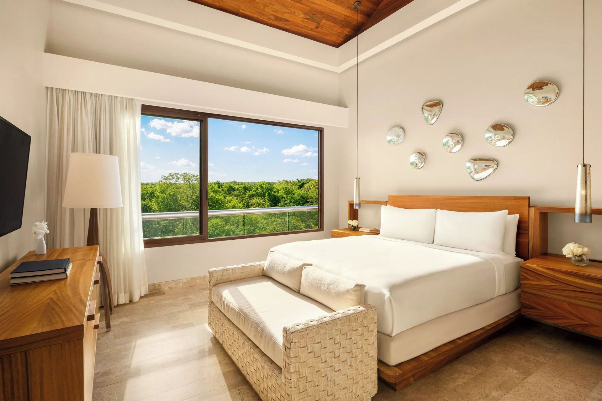 King bedroom with woven bench and wide treetop window at Fairmont Heritage Place Mayakoba.