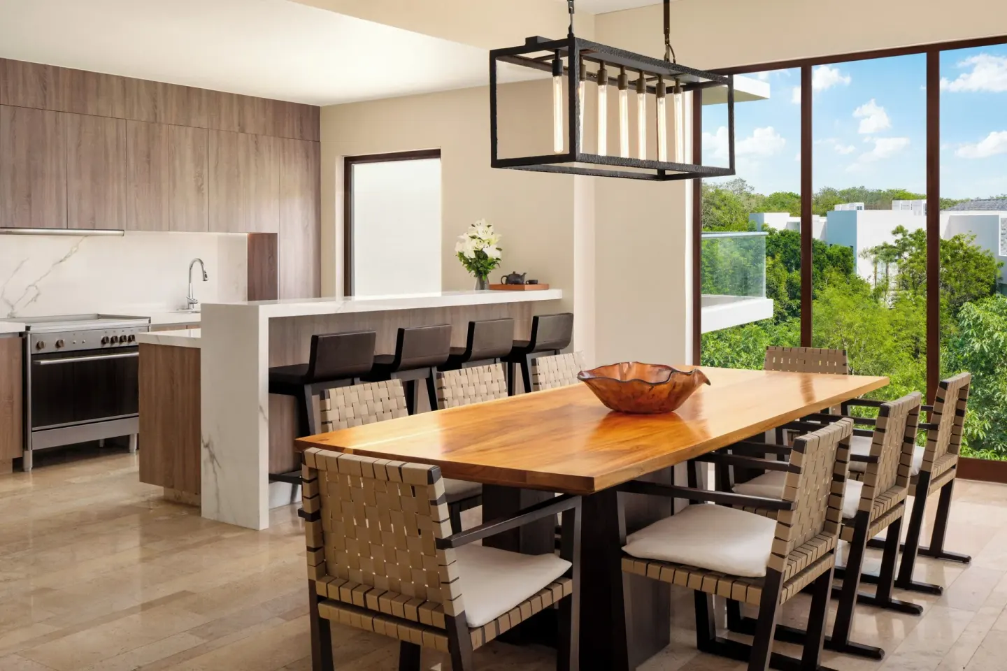 Open kitchen and dining table with floor-to-ceiling windows at Fairmont Heritage Place Mayakoba.