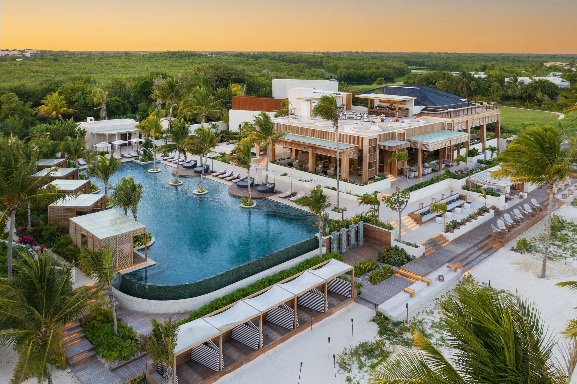 Aerial view of pools, beach deck, palms, and resort buildings at Fairmont Mayakoba.