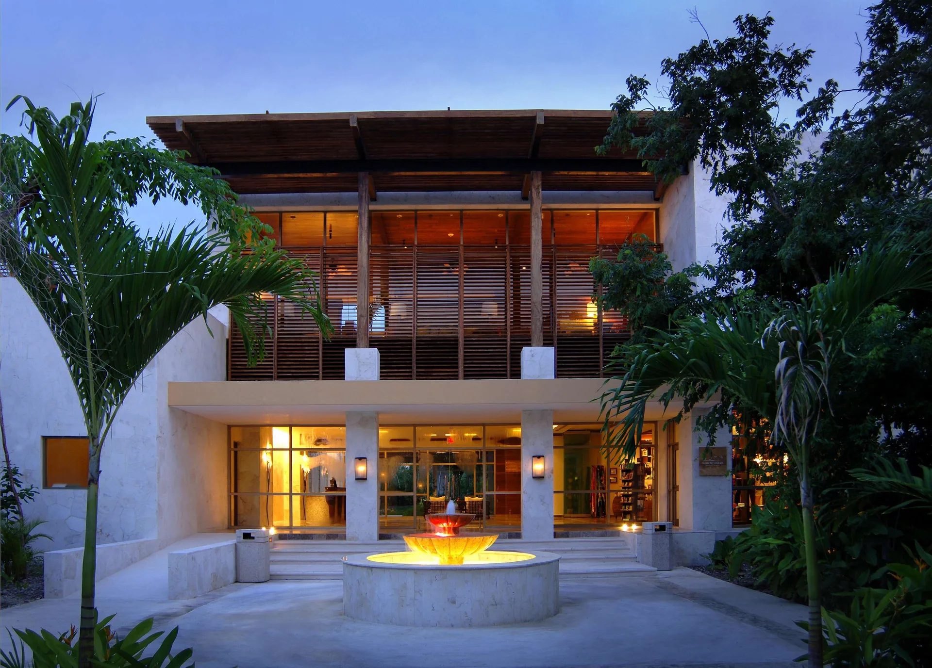 Evening resort entrance with a lit fountain and tropical landscaping at Fairmont Mayakoba.